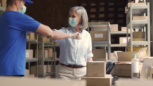 Warehouse Workers Wearing Face Masks Giving Elbow Bump at Meeting