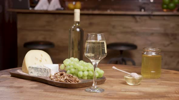 A Bottle and a Glass of Wine Combined with Cheeses