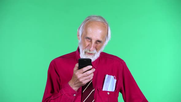 Portrait of Happy Old Aged Man 70s Talking for Mobile Phone, Isolated Over Green Background.