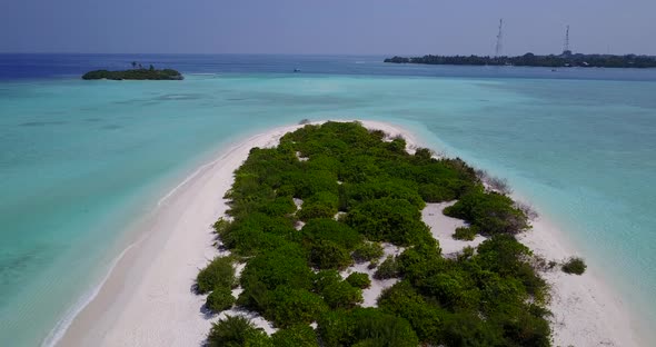 Wide flying island view of a sandy white paradise beach and turquoise sea background in vibrant 4K