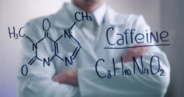 Man Scientist Thinks Over the Solution of Chemical Formula of Caffeine Drawn on a Glass Board in a