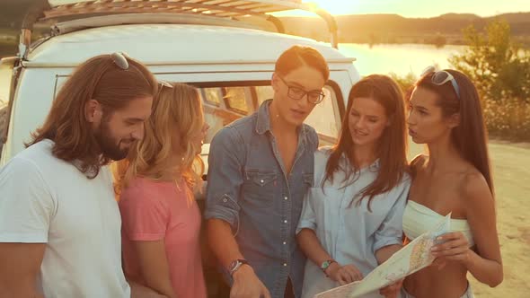 Summer Travel. Friends Using Map Near Car In Nature. Happy Smiling People