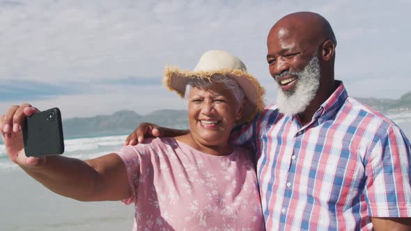 Mixed race senior couple taking a selfie with a smartphone at the beach