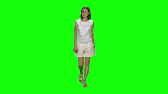 Young Woman with Brown Haircut Is Calmly Walking on Green Screen. Chroma Key. Front View. Slow