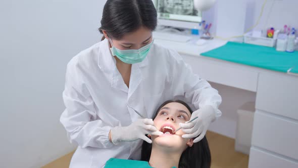 Asian young dentist doctor wearing face mask, examining for cavities and gum disease for oral care.
