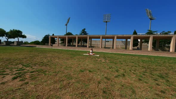 Girl in White Dress Doing Stretching Exercises on the Grass at Sunny Day