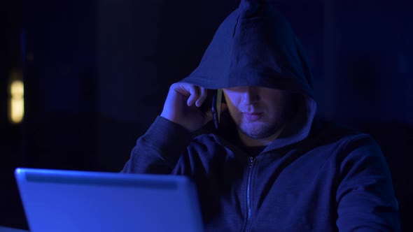 Hacker with Laptop Calling on Cellphone 10