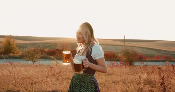 Lush Girl in Ethnic Dress Poses at Camera with Pints of Beer in Hands on Nature