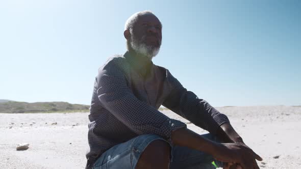 Senior man sitting on the sand at the beach