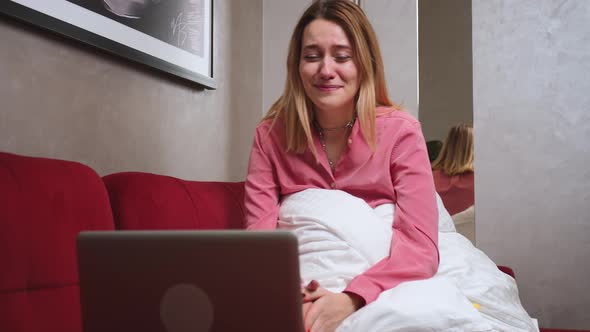 Woman Crying at Home on Sofa While Looking at Laptop