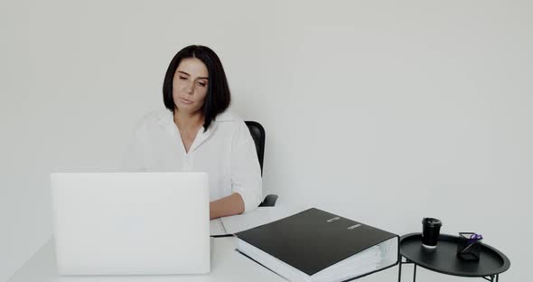 Female Teacher Conducts an Online Lecture on a Laptop on Background in Office