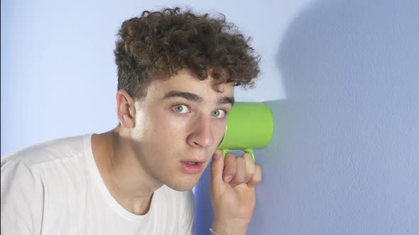 Surprised Teenager Young man; listen overhears like a spy by Using green Cup 