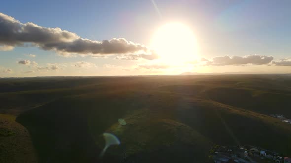 Drone Flying Slow Motion Towards Hills with Sun Glare Reflecting