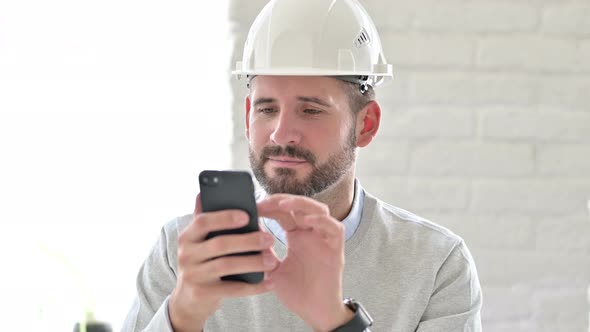 Portrait of Cheerful Young Engineer Using Smartphone