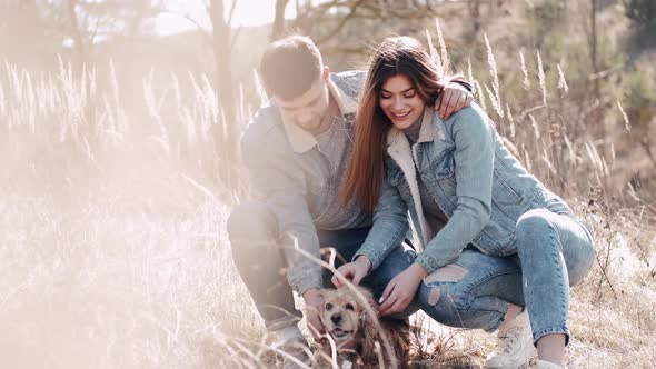 The Loving Couple Is Sitting with a Dog and Smiling in the Wheat Field