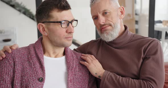 Gay LGBT Man Puts Head on Shoulder of Partner Hugging at Home