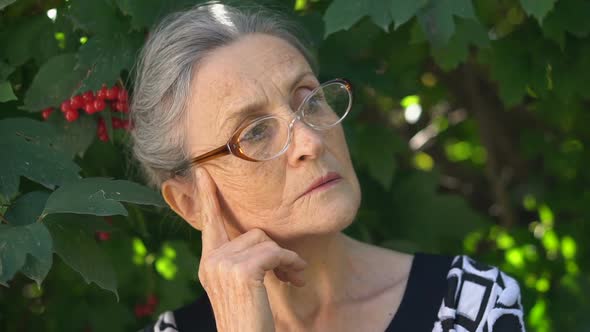 Closeup Portrait of Upset Senior Mature Woman in Eyeglasses Regreting About Something and Holding