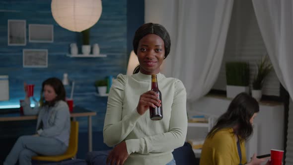 Happy Woman with Dark Skin Drinking Beer Having Fun During Holiday Party