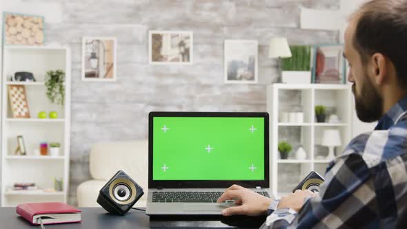 Zoom in Footage of Man Looking at Laptop with Green Screen