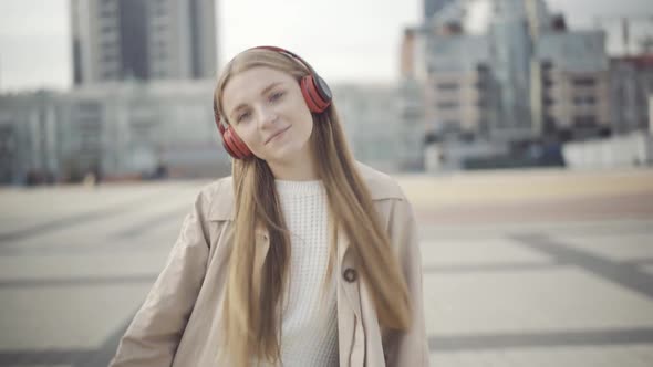 Middle Shot of Cheerful Young Woman in Headphones Dancing on Urban City Square on Cloudy Autumn