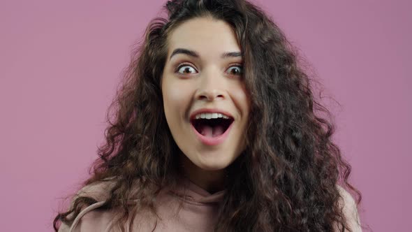 Closeup Portrait of Excited Young Woman Smiling and Expressing Happiness on Pink Background