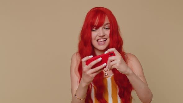 Worried Funny Addicted Redhead Girl Enthusiastically Playing Drive Racing Video Game on Mobile Phone