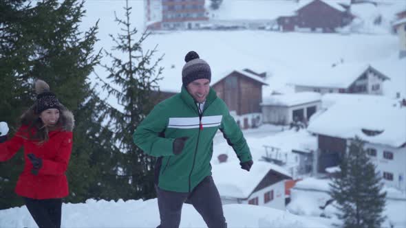 A man and woman couple having a playful snowball fight lifestyle in the snow at a ski resort