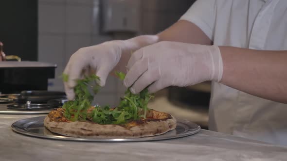 Closeup of Male Hands in Gloves Adding Greenery on Pizza in Restaurant Kitchen