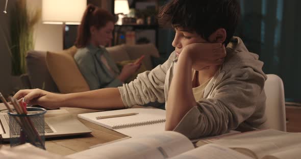 Young student sitting at desk at home and doing his homework, learning and education concept