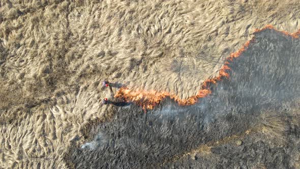 Aerial View of Firemen Extinguishing Grassland Field Burning with Red Fire During Dry Season