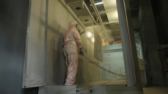 Worker in Protective Suit Sprays Powder Paint From Gun on Metal Products