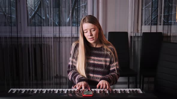 A Young Girl with Long White Hair Plays the Piano and Sings a Song