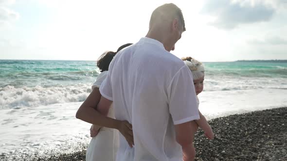 Charming Little Asian Girl Looking at Camera As Happy Interracial Parents Holding Hands Walking Away