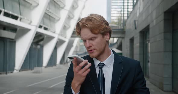 Successful Businessman Recording Voice Message Standing Outdoors at Business District