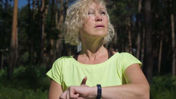 Blonde Aged Woman Checks Pulse on Fitness Bracelet Closeup