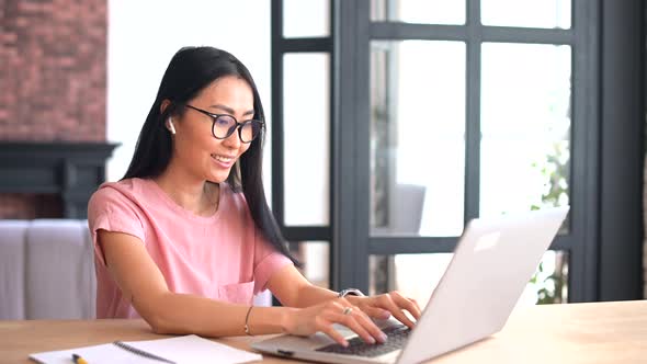 An Attractive Young Asian Woman is Using a Laptop for Remote Work