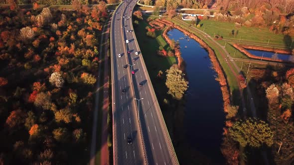 4K AERIAL: Cars and semi truck driving on busy highway across the country in beautiful autumn evenin