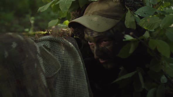 Closeup of Sniper in Disguise Sniper Coat Applying Camo Paint on Face alt