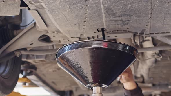 Car Repairman Engine Oil Drain In Workshop