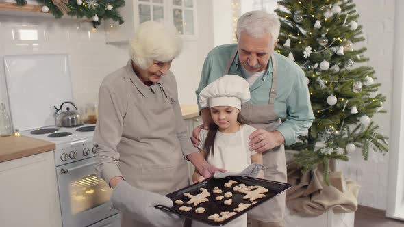 Grandparents and Granddaughter Posing with Cookies on Christmas Day