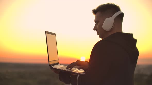 A Man in Headphones on the Roof Relaxes Working Remotely Enjoying Life Despite a Handsome Kind of