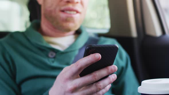 Happy albino african american man with dreadlocks sitting in car using smartphone