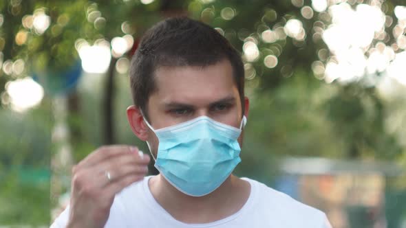 Male Man with Wireless Headphones in a Medical Protective Mask Online Listening Music During Self