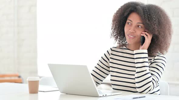 African Woman with Laptop Talking on Smartphone 