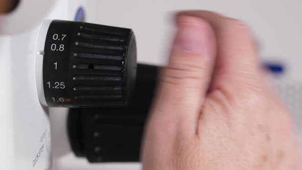 Hand of Microbiologist Setting Up Microscope
