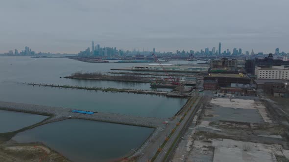 Forwards Fly Above Old Piers in Abandoned Docks in South Brooklyn with View of Manhattan and Its