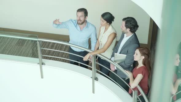 Business professionals meeting in corridor overlooking building atrium