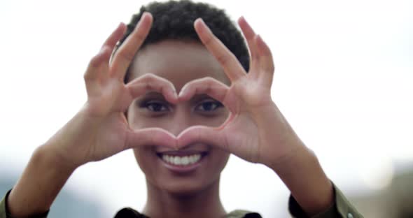 African Teenager Smiles with White Teeth Puts Hands in Front of Her Shows Fingers Heart Shape Sign