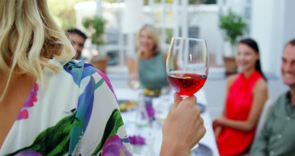 Friends applauding woman while having glass of wine