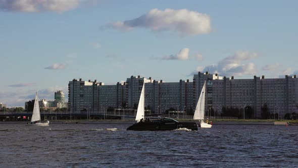 Yacht Sailboats Sailing Against the Background of the City and Residential Buildings